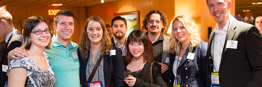 Group of alumni standing while smiling at the camera