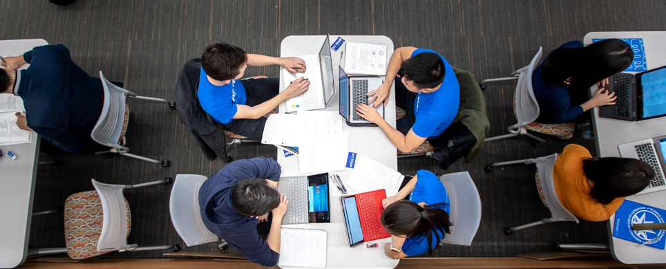Birds-eye view of students sitting a table on their laptops.