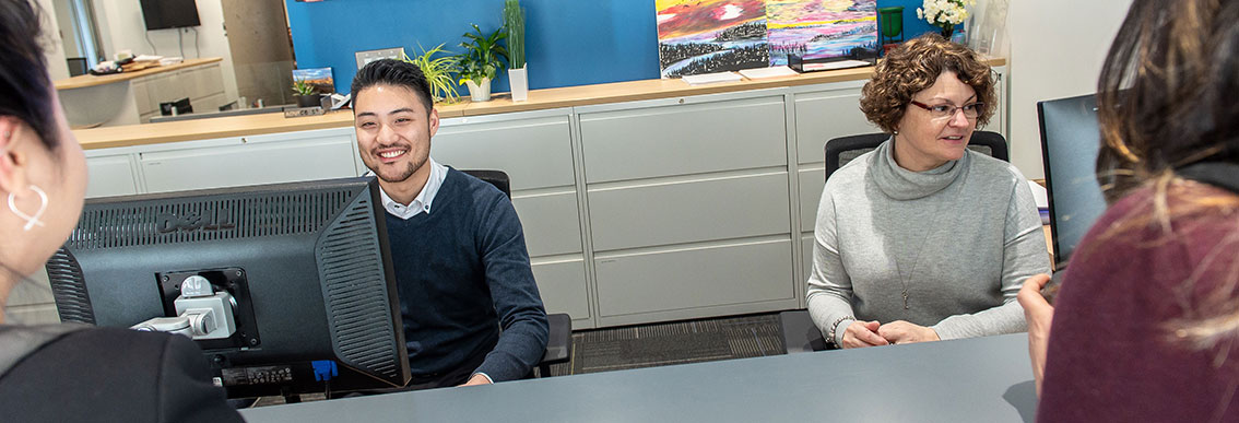 Science advisors sitting at a front desk looking out towards students who are off camera.