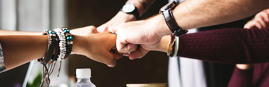 Four hands in a group fist bump.
