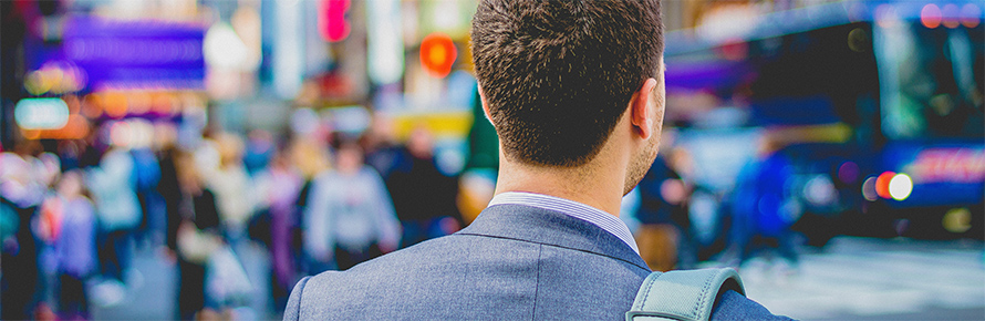 The back of a man's head as he walks in a city.