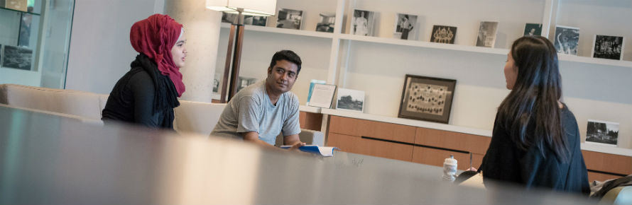 Three students sitting at a table in conversation.