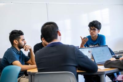 Students sit around a round table in discussion.