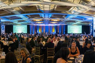A large party gathering with people sitting around round tables.