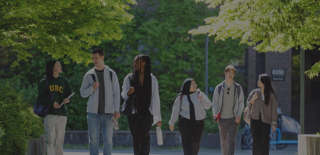 A group of students walking in a row along a tree lined path.