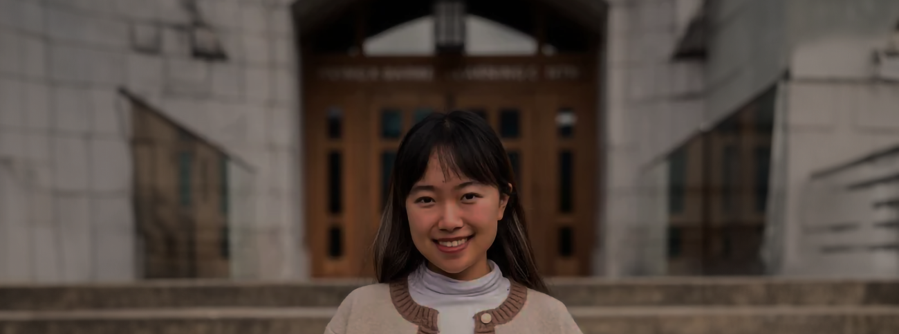 Young woman wearing white sweater and smiling into camera