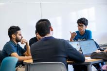 Students sit around a round table in discussion.