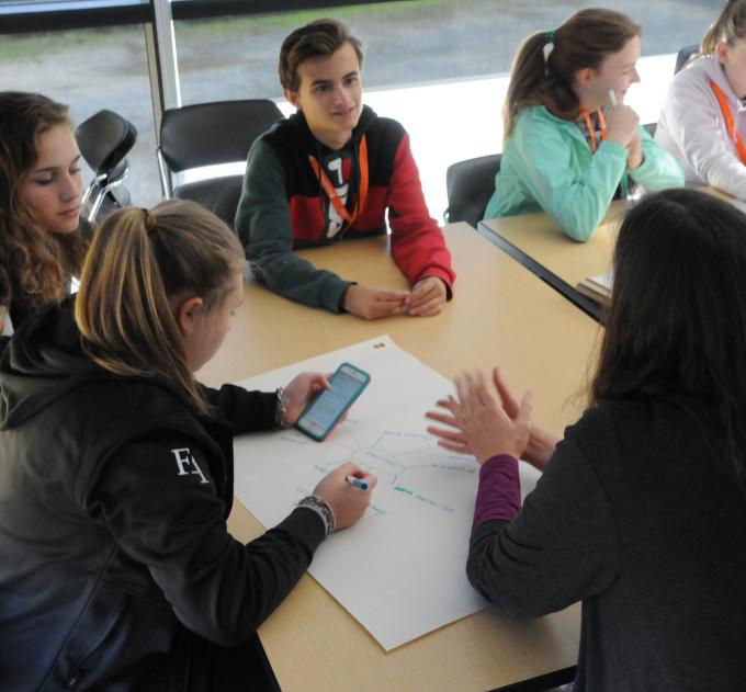 A group of young students sit around a table in conversation