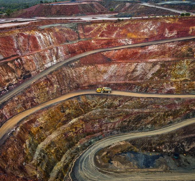 Yellow truck drives along a winding path inside an open cast mine in New South Wales, Australia.